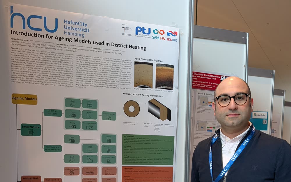 Pakdad Langroudi neben seinem ISEC-2026-Poster „Introduction for Ageing Models used in District Heating“